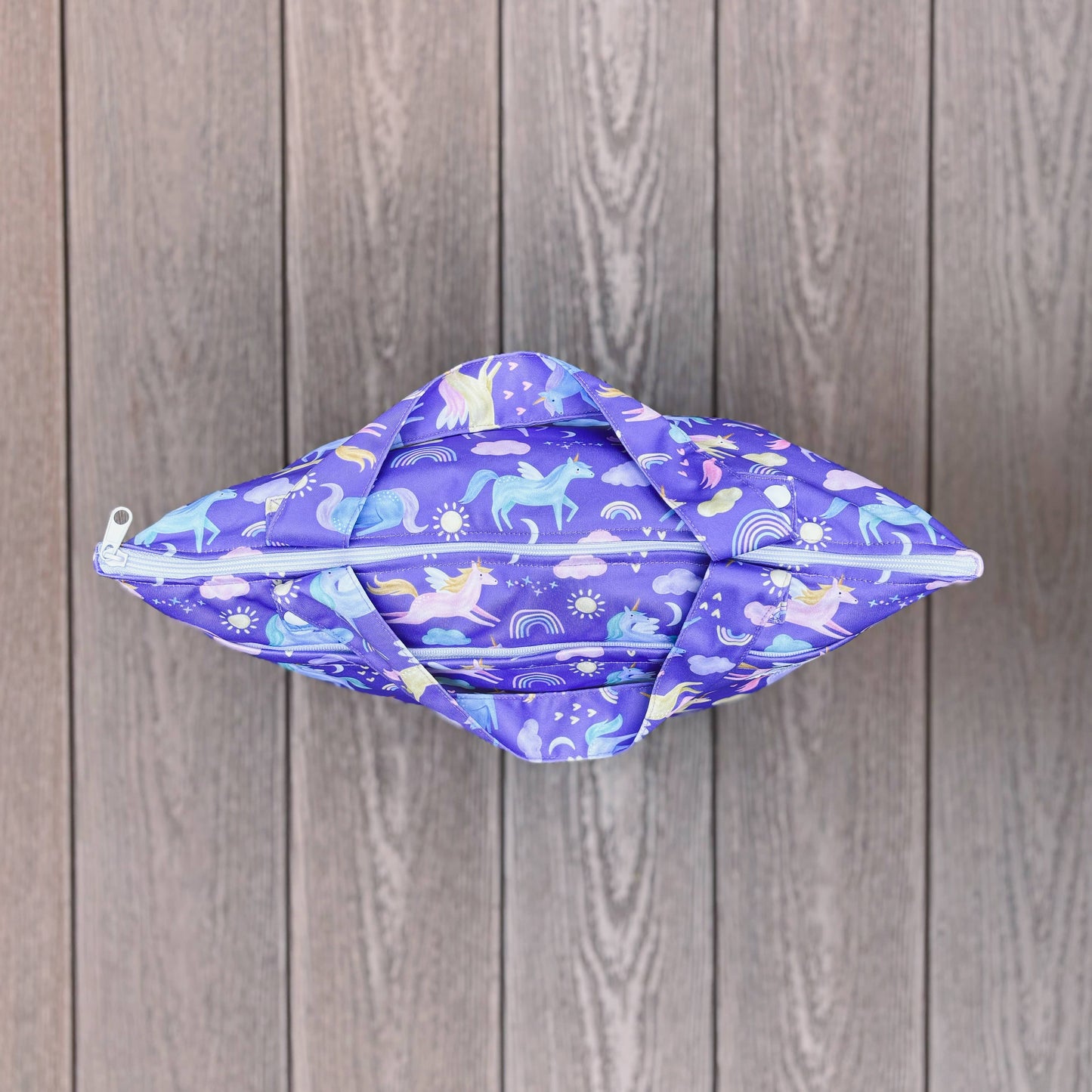 Purple fabric pouch with unicorn pattern on a wooden surface