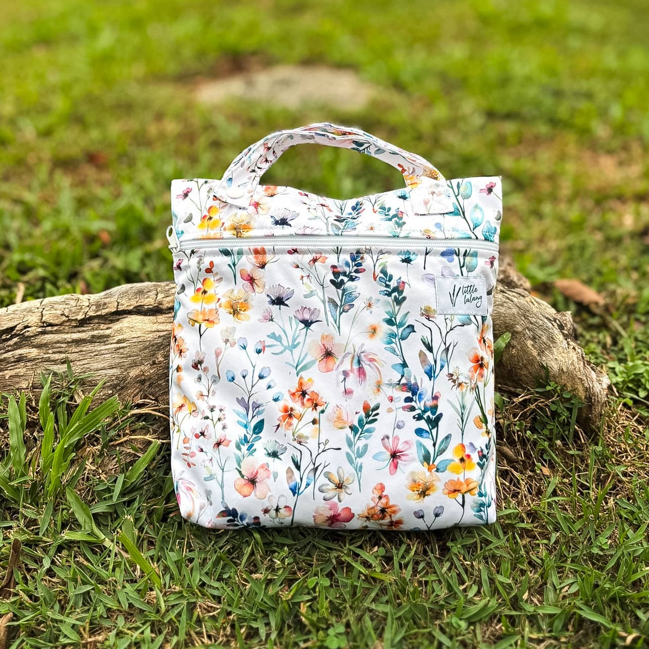 Floral-patterned bag on a grassy outdoor background